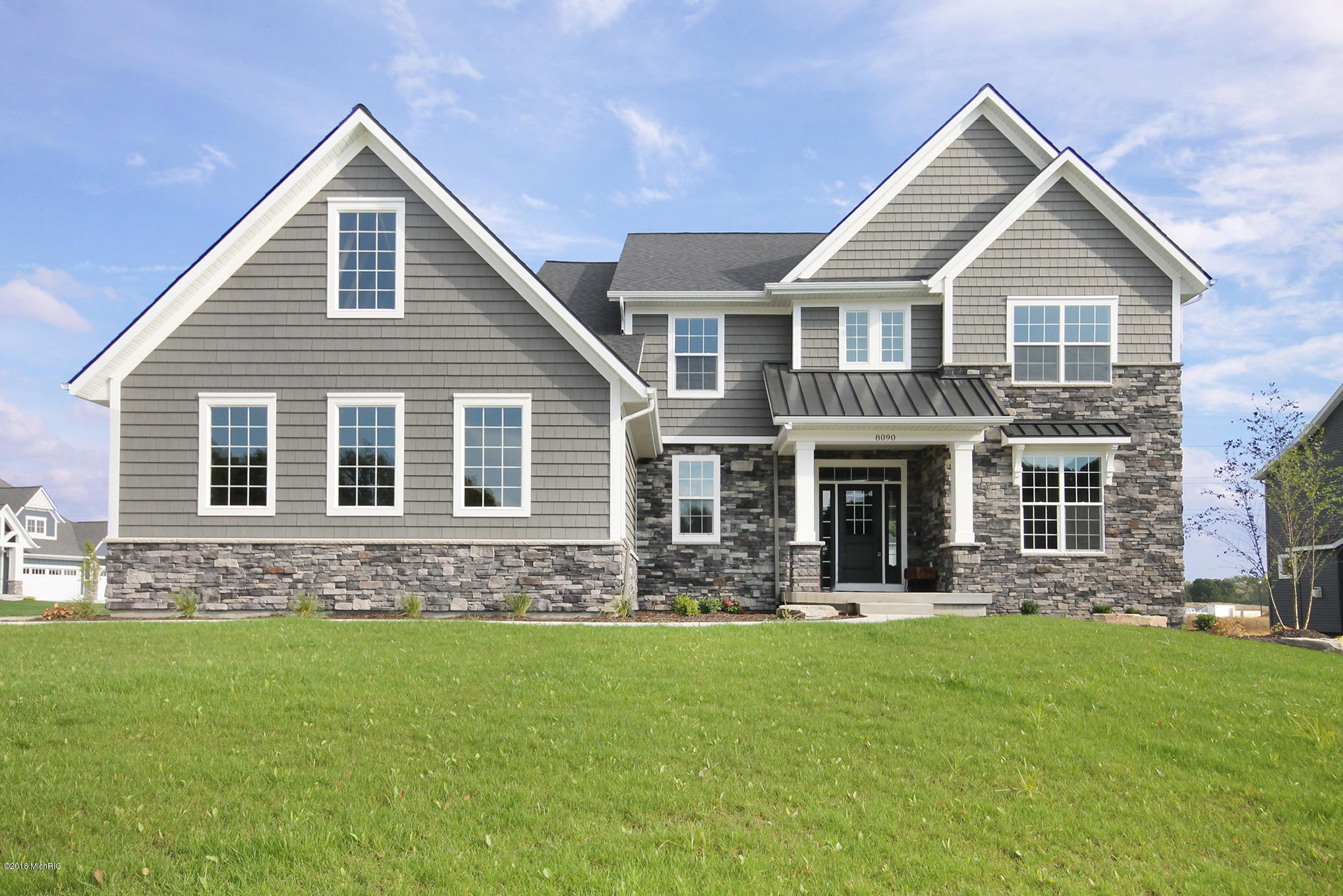 Exterior of new home with grey siding and stone detailing, 