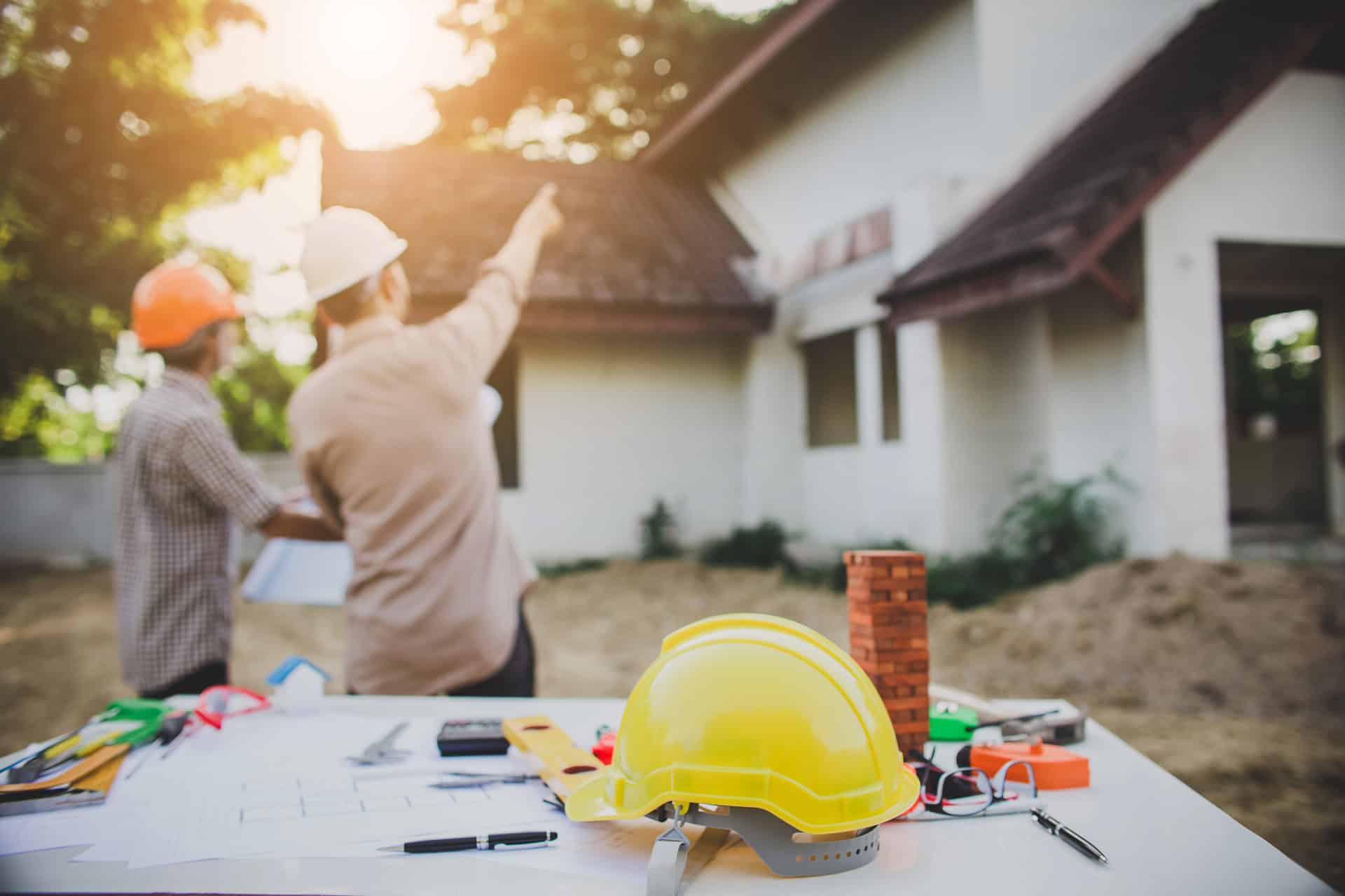 Construction workers pointing at the custom home they are building. 